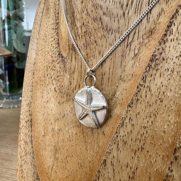 Silver starfish medallion pendant on display stand