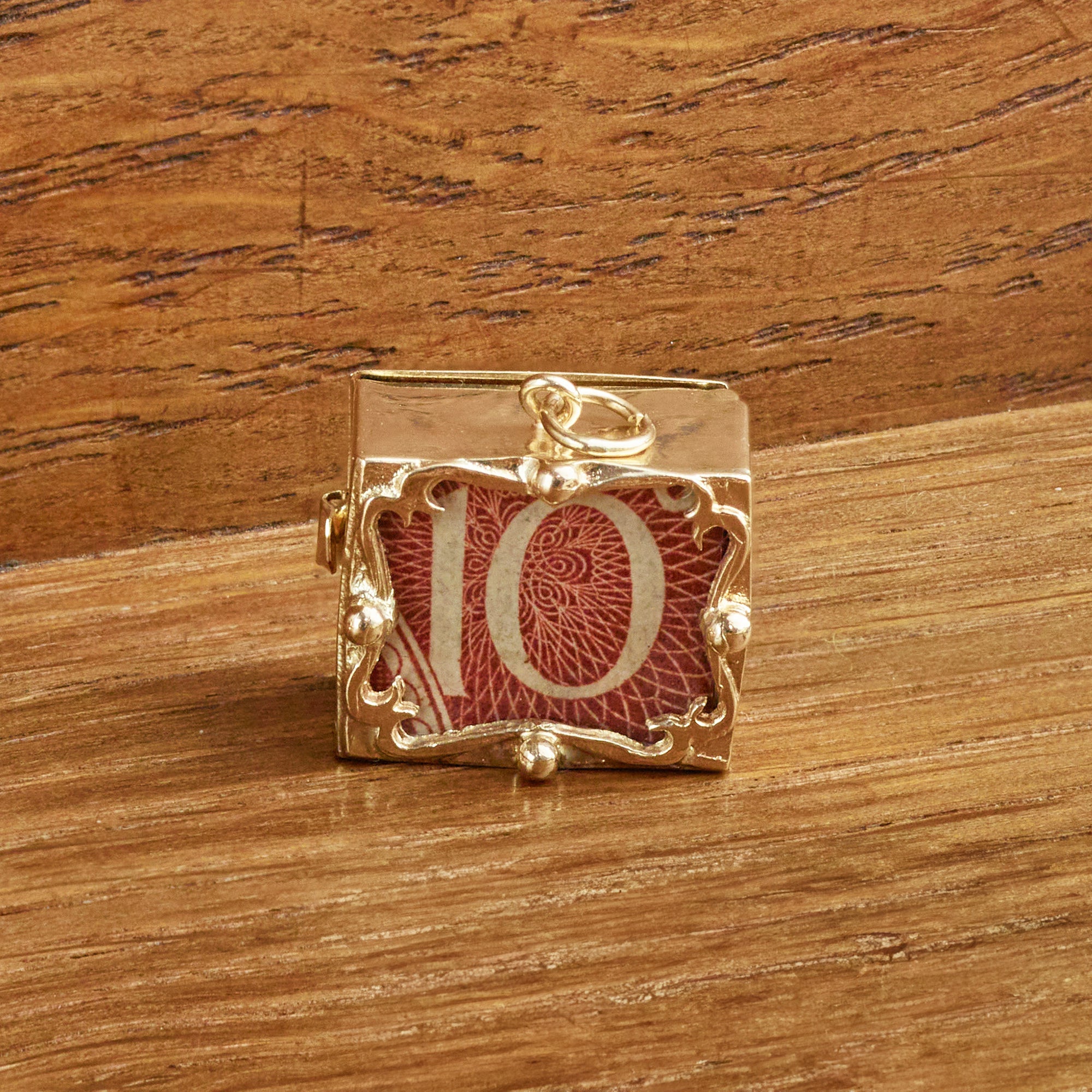 Gold Shilling Charm 1960's on Wood Background